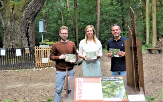 Am Kraftort „De Decke Boom“ in Kreuzau-Stockheim stellen Dennis Winands (Rureifel Tourismus), Lea Schenkelberg und Nicolas Gath (beide Naturpark Nordeifel) die Broschüre mit kurzen Wandertouren zu den 15 Kraftorten vor. (v.l.n.r.) <span class="copy">&copy; Naturpark Nordeifel</span>